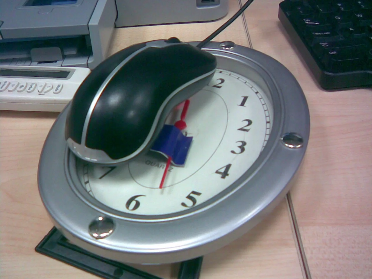 Myszka komputerowa postawiona na zegarze z sekundnikiem